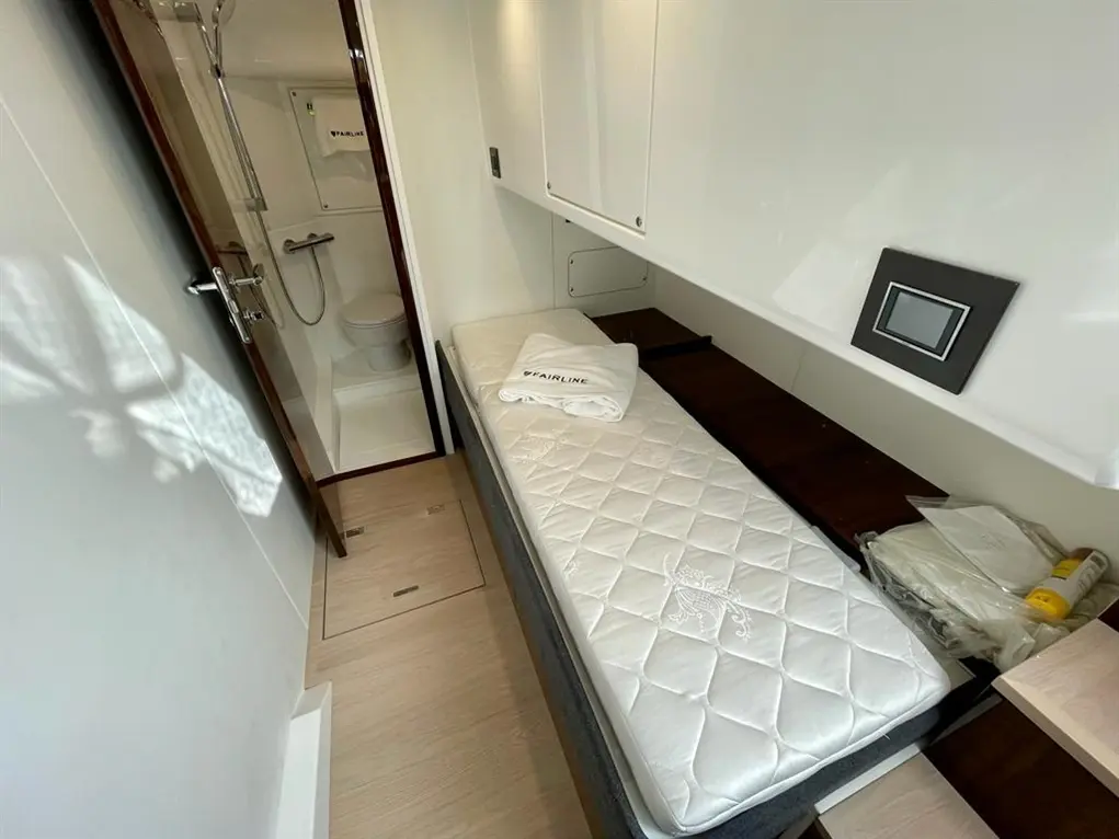Compact cabin featuring a bed with a white mattress, storage space, and a bathroom door in the background.
